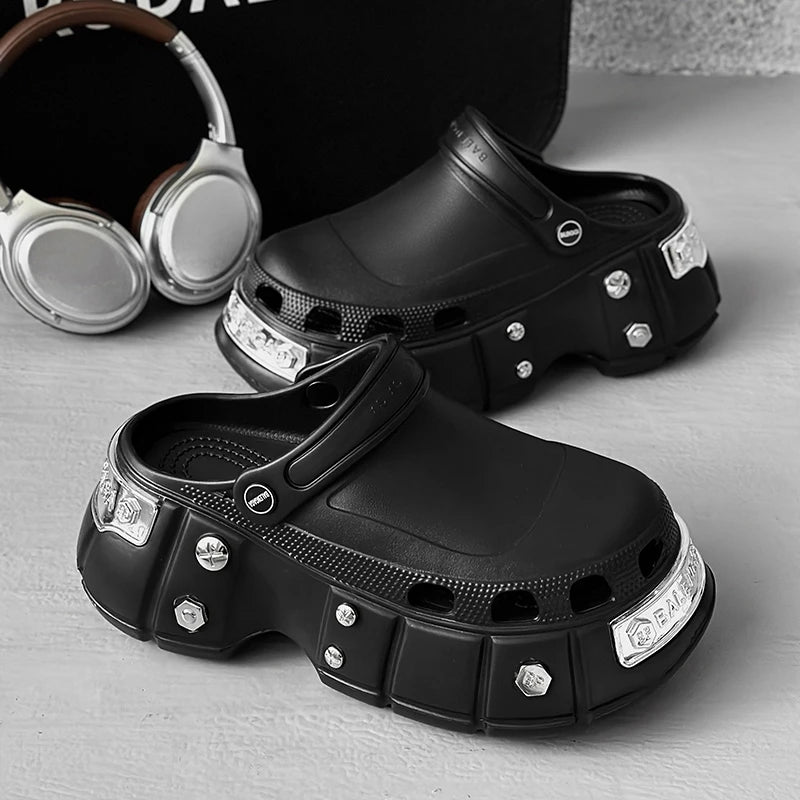 Black clogs with decorative elements on a gray surface, with headphones in the background.