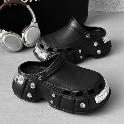 Black clogs with decorative elements on a gray surface, with headphones in the background.