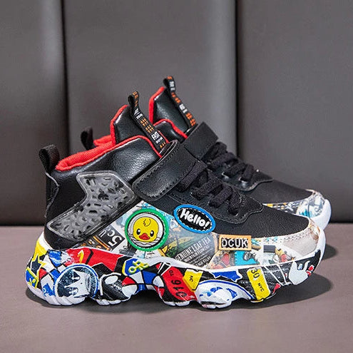 A pair of black high-top sneakers with colorful graffiti-style stickers and red accents, shown in two views against a dark gray padded background.