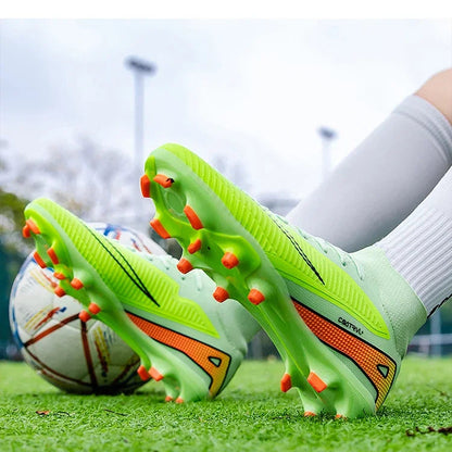 Green soccer cleats with orange spikes on a grass field, with a ball nearby.