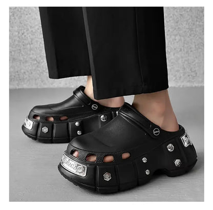 Black clogs with silver accents worn by a person on a gray background