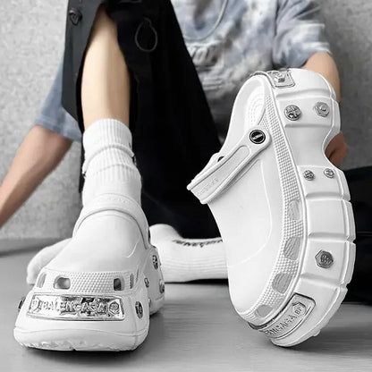 White chunky platform sandals with silver hardware accents, shown on a model sitting down against a gray background.