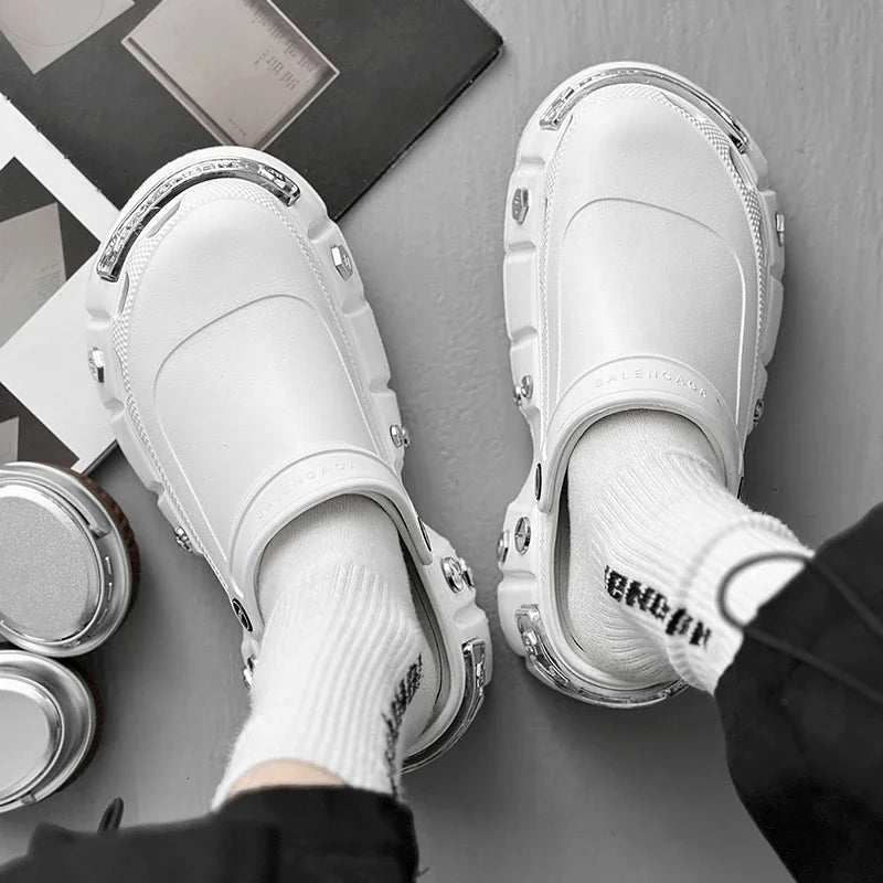 White slip-on shoes with metallic accents worn by a person on a gray surface.